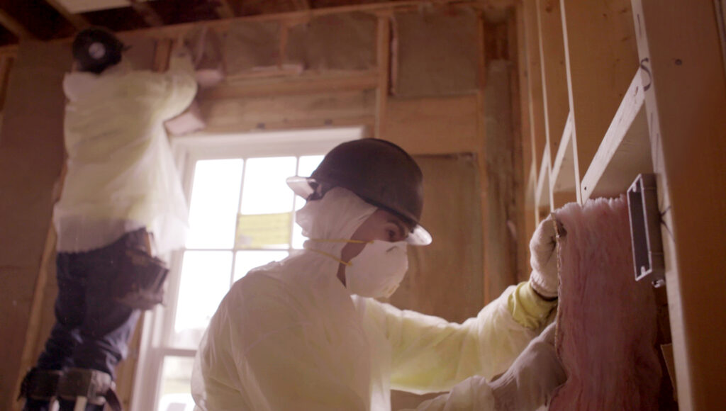 Person installing insulation in a home's walls